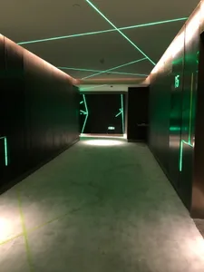Modern interior hallway with metallic cladding and illuminated green lines.