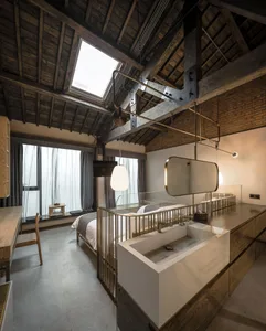Modern industrial-style bedroom with wooden beams and skylight.