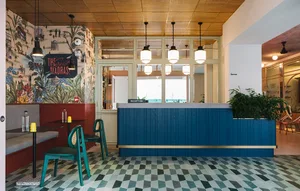 A modern coffee shop with a blue wooden counter, industrial-style decor, and a patterned floor.