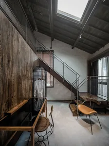 A modern industrial living space with wooden furniture, concrete walls, and wire-mesh accents.