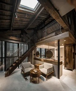 An industrial loft featuring white furniture and a moneybox, with wooden beams and a skylight.