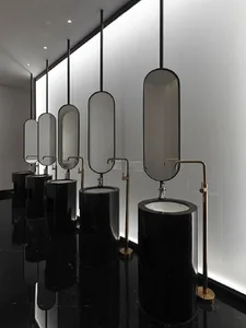 A row of sophisticated, modern public restrooms featuring sleek, black marble sinks and oval-shaped mirrors.