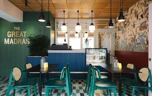 A modern coffee shop with wooden walls, blue tables, and green chairs.