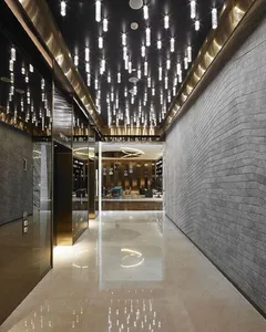 A modern corridor with concrete walls and floor, featuring cascading lights from the ceiling.