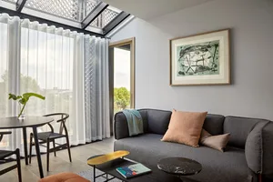 A modern living room featuring a fabric sofa, glass coffee table, and marble side table.