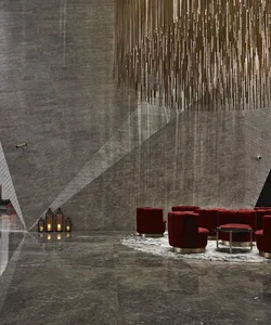 Modern lobby with concrete walls, red chairs, and metal lighting fixture