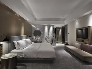 A modern bedroom featuring a white marble bed, minimalist design, and sleek metal bedside table and television console.
