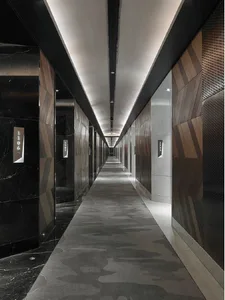 A modern, sleek corridor lined with marble floors, wooden walls, and metallic elements.