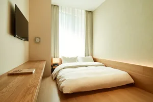 Modern minimalist bedroom featuring a white bed and wood elements.