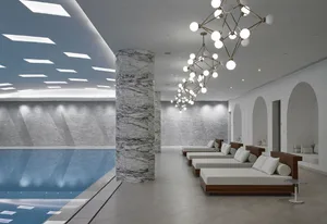 A modern spa relaxation room featuring marble columns, concrete walls, and wooden lounge beds.