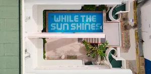 Swimming pool with tiled bottom displaying the words 'While the Sun Shines'.