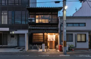 A traditional Japanese storefront with wooden and paper elements, featuring a clay sculpture on the porch.