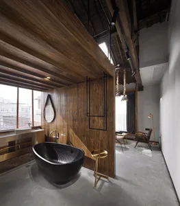 Modern industrial bathroom featuring a freestanding marble bathtub, wooden ceiling beams, and metallic accents.