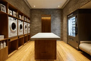 A modern industrial laundry room with wooden flooring, white washing machines, and a wooden table.