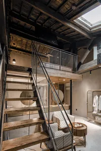 Industrial-style loft interior with metal staircase, concrete walls, and wooden stairs.
