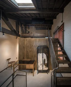 An industrial office space featuring wooden elements, a spiral staircase, and a loft area.
