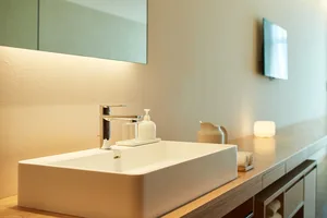 Modern bathroom with a sleek, minimalist design featuring a ceramic sink and countertop.