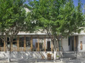 A stone restaurant exterior with wooden chairs and a glass facade.