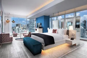 Modern hotel room interior with wooden furniture, fabric accents, glass walls, and metal elements.