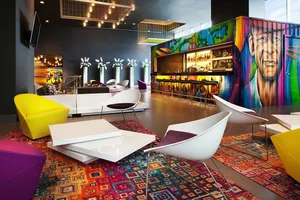 A modern lobby with colorful furniture, a bar, and a mural.
