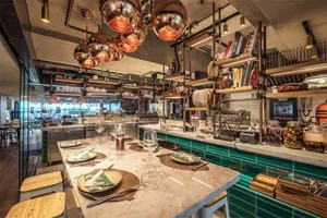 A modern restaurant interior featuring metallic decor and green tiles