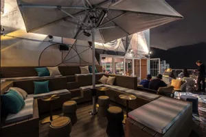 Industrial-style rooftop lounge with wooden seating and fabric cushions.