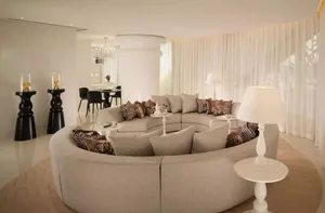 Modern luxury living room with a circular sofa, patterned cushions, and white tables.