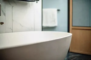 Modern minimalist bathroom with a white ceramic bathtub and marble tiles.