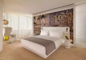 A modern bedroom with a white bed and decorative wall patterns.