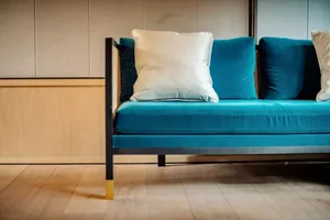 A modern blue velvet sofa with white cushions in a living room setting.