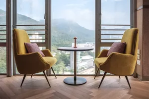 Modern home office featuring wooden flooring, fabric chairs, and a metal table with a mountain view.