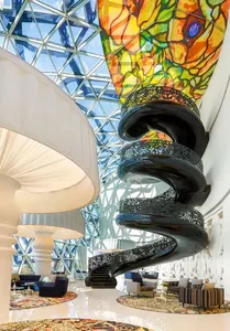 A modern hotel lobby featuring a black metal spiral staircase with intricate designs.