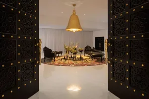 A luxurious modern living room with black furniture, gold pendant light, and round rug.