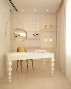 A modern office workspace with a sleek, white marble desk and chair, under a glowing, spherical light fixture.