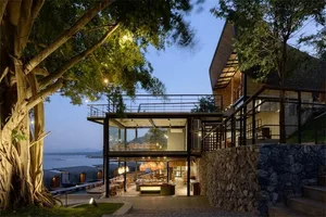 A modern two-level residential building featuring glass, metal, and stone materials.