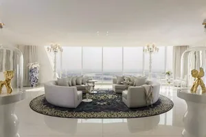 A luxurious, modern living room with white marble flooring, large windows overlooking a scenic view, and circular sofas arran