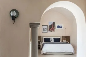 A minimalist bedroom with a concrete wall, a wooden bed frame, and fabric bedding.
