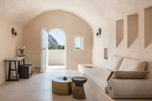 A minimalist living room with concrete flooring, a leather sofa, and a small table.