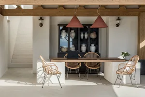 Modern minimalist dining room featuring concrete flooring, rattan chairs, and a wooden dining table.