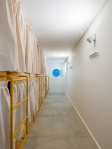 A minimalist dormitory hallway with curtains and yellow steel railings.