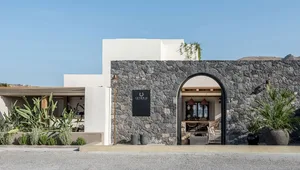 Stone exterior of a minimalist restaurant with an arched entrance and modern design elements.