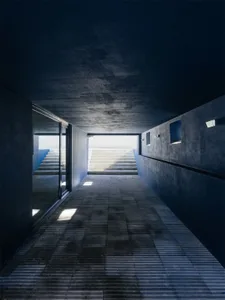 Concrete staircase leading up to a bright, open space, with minimalist architecture.