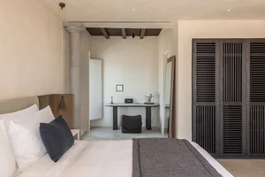 A modern bedroom featuring concrete walls and wooden furniture.