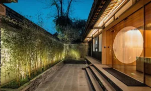 Modern residential entryway with wood flooring, lighting, and a circular glass door.