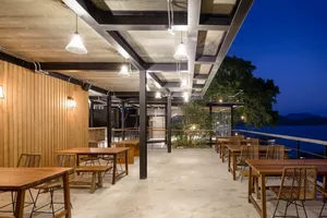 Modern, industrial-style restaurant featuring wooden tables and concrete floors under a steel beam ceiling.