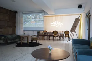A modern living room with a mix of blue and brown color schemes, featuring wooden furniture and a large screen showing a bowl