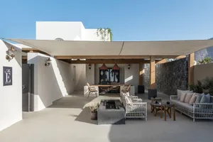 A modern, minimalist patio featuring concrete flooring, a fire pit, and outdoor seating.