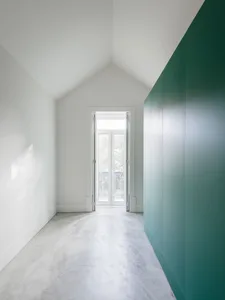 A white closet with a green door on a concrete floor.