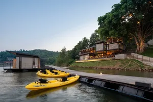 Modern resort lodge with concrete and glass exterior, featuring wooden dock and kayaks.