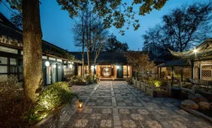 The exterior of a residential building featuring brick and concrete materials, illuminated by warm lights during dusk.